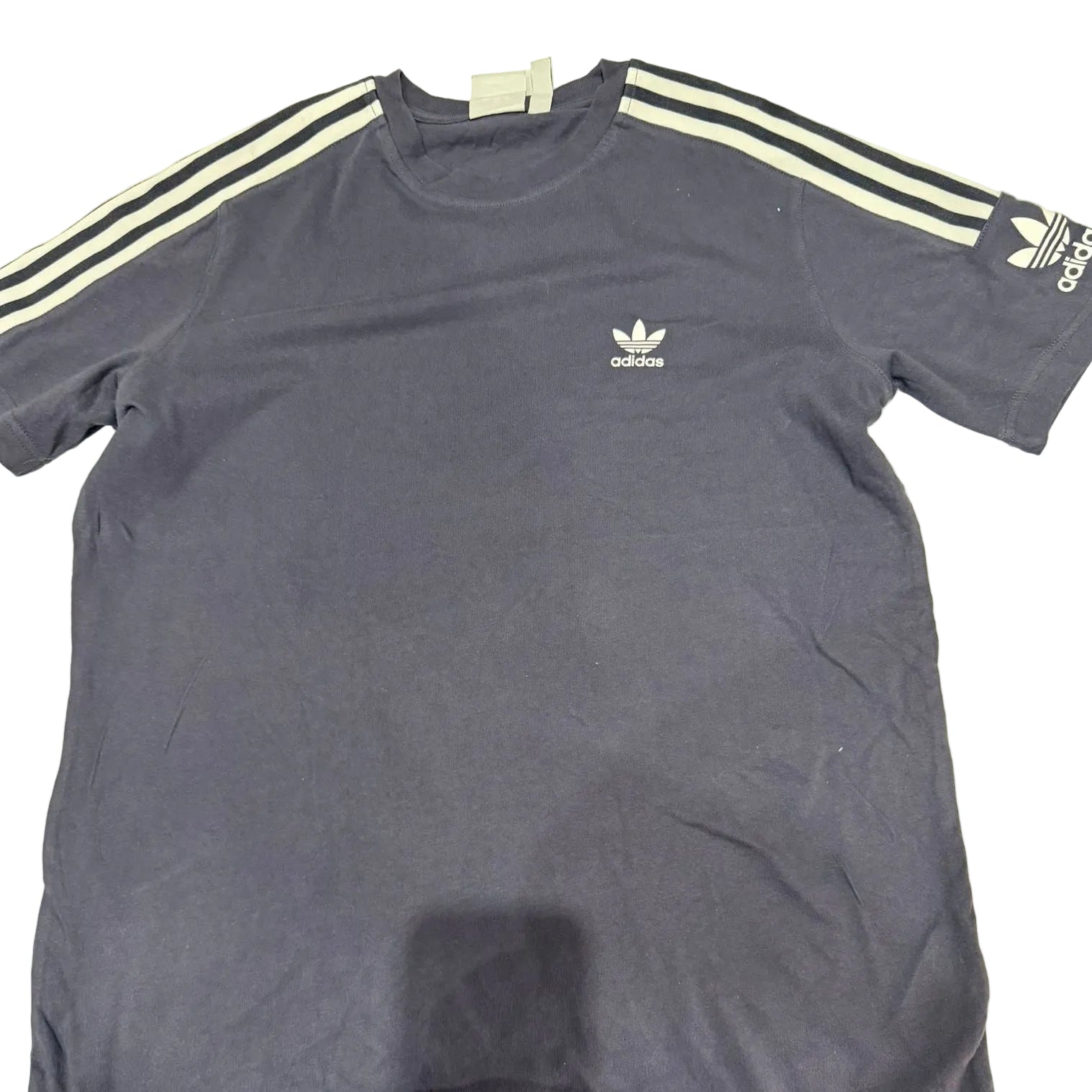 Blue Adidas t-shirt with white stripes on a light surface